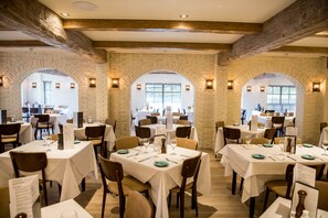 A restaurant with brick walls, white tables, and brown chairs. - Briar Court Hotel (Huddersfield)