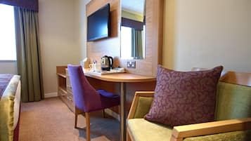 A hotel room with a bed, a desk with a chair, a television, and a mirror.