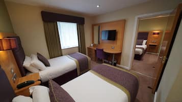 A hotel room with two beds, a desk, a chair, a TV, and a mirror.