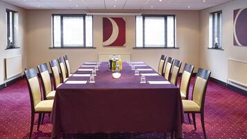 A conference room with a long table, chairs, and a red carpeted floor.