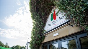 Um restaurante chamado Da Sandro, com uma placa parcialmente coberta por hera.
