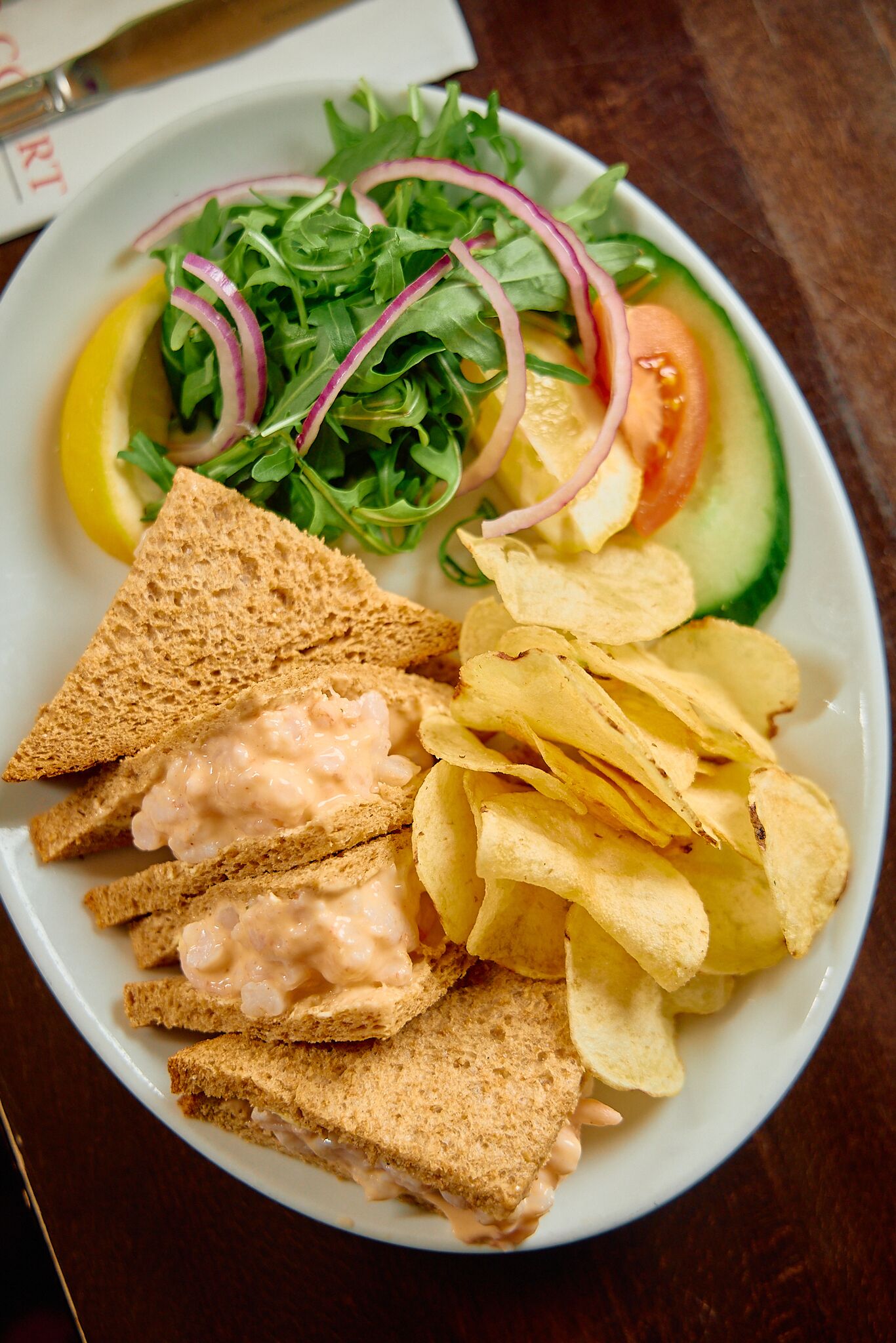 Ein Teller mit Salat, Chips und Sandwiches.