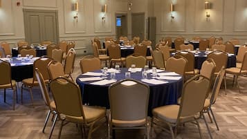 Une salle de conférence équipée de tables rondes, de chaises et de lustres.
