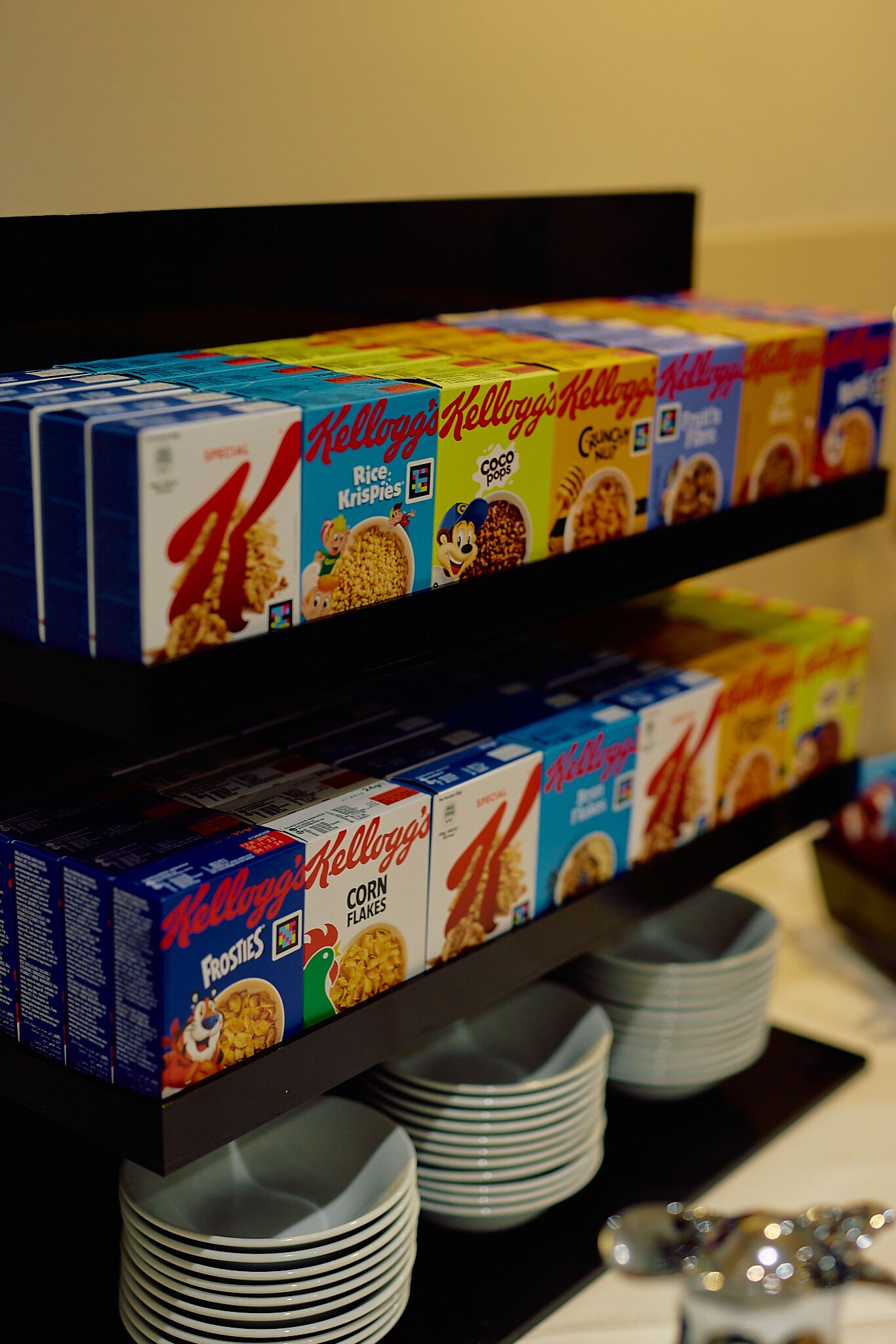 A shelf stocked with various Kellogg's cereal boxes.