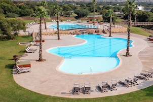 Una piscina al aire libre, sombrillas, sillones reclinables de piscina