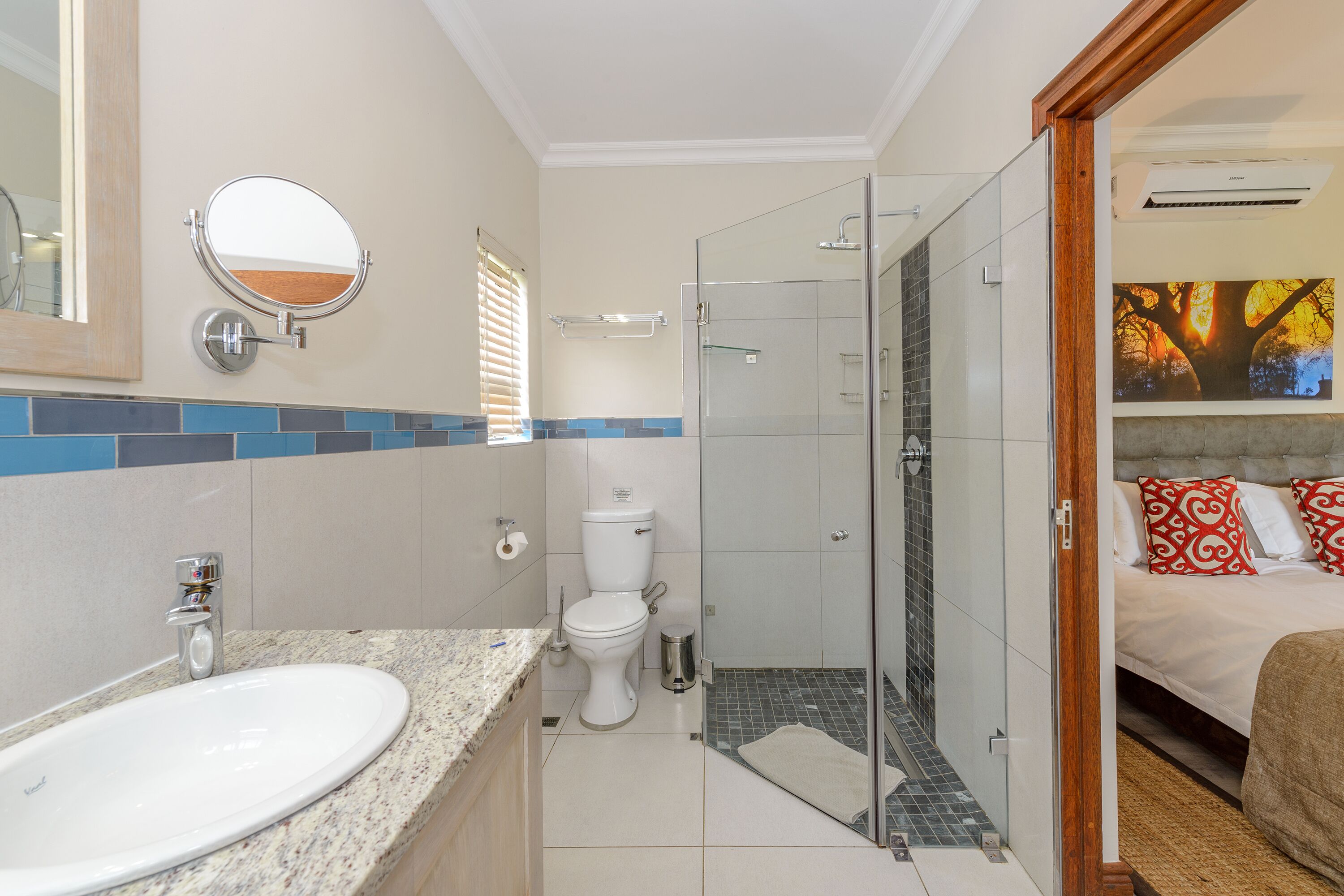 Une salle de bain équipée d’un lavabo, de toilettes et d’une douche à parois de verre.
