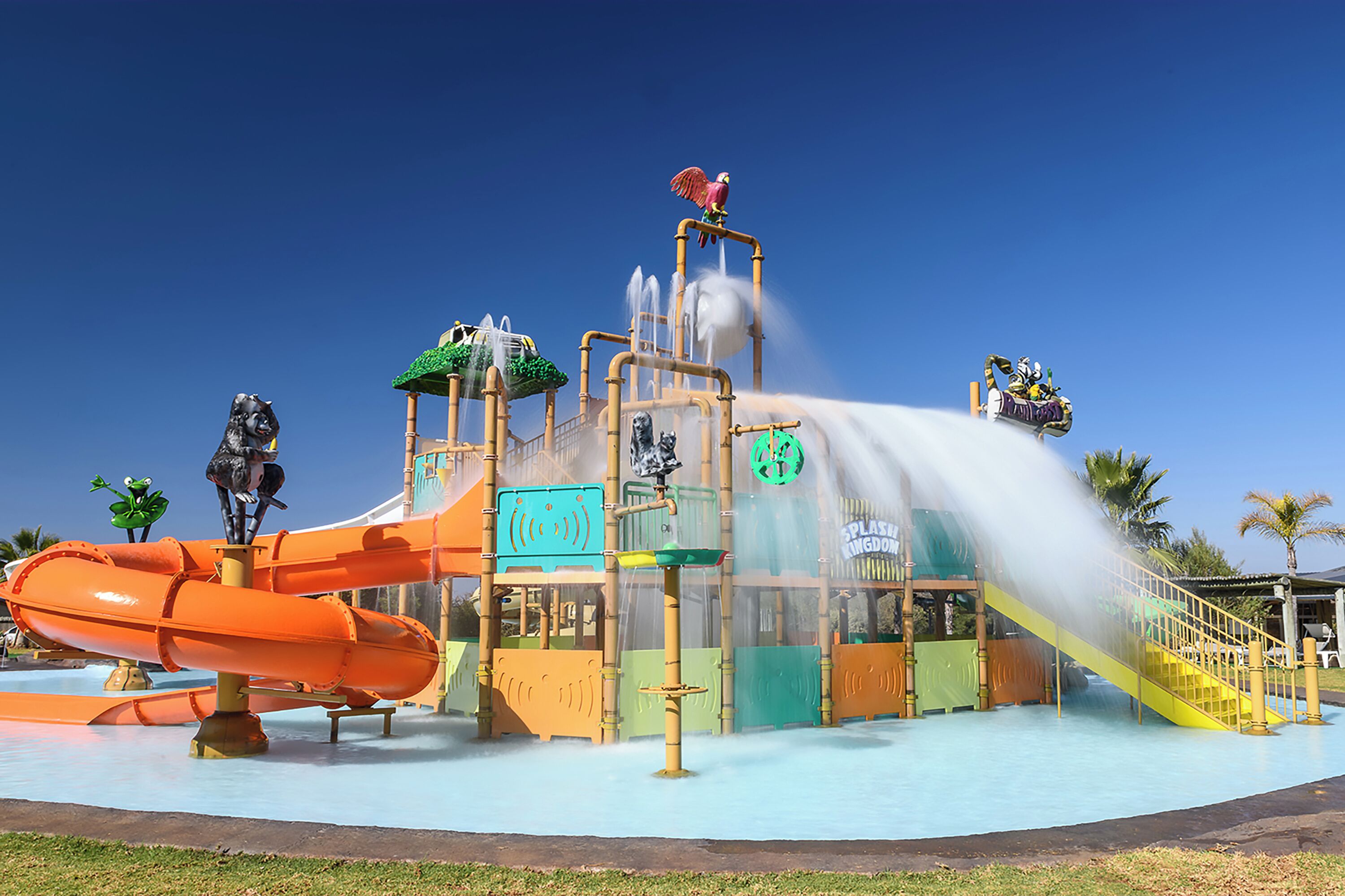 Um parque aquático com um tobogã, uma fonte de água e uma estátua de um cavalo.