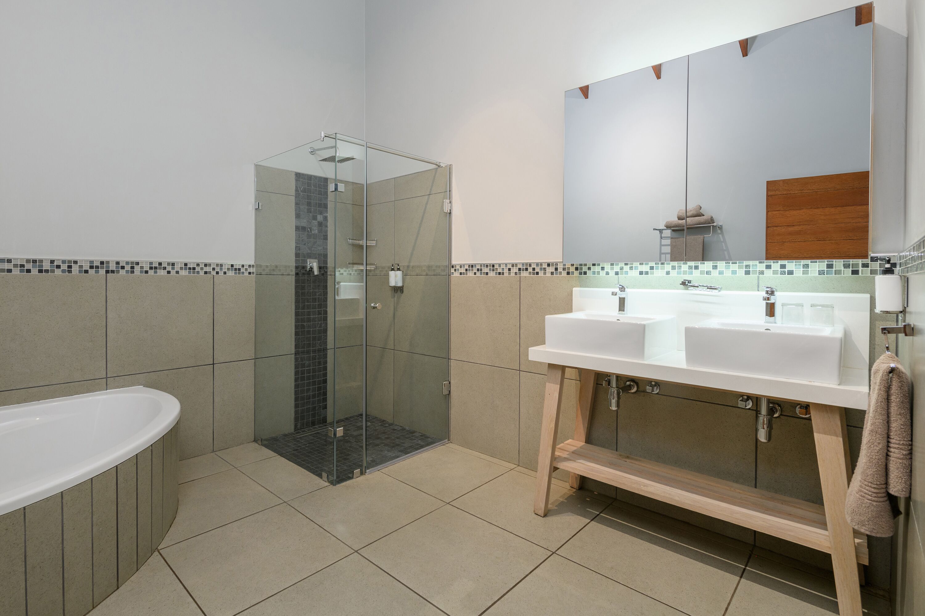 Un baño moderno con cabina de ducha de vidrio, bañera independiente y tocador doble.