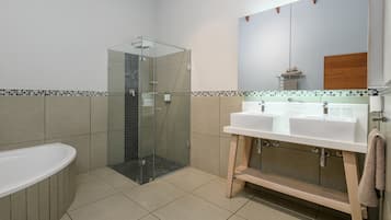 A modern bathroom with a glass shower enclosure, a freestanding bathtub, and a vanity with dual sinks.