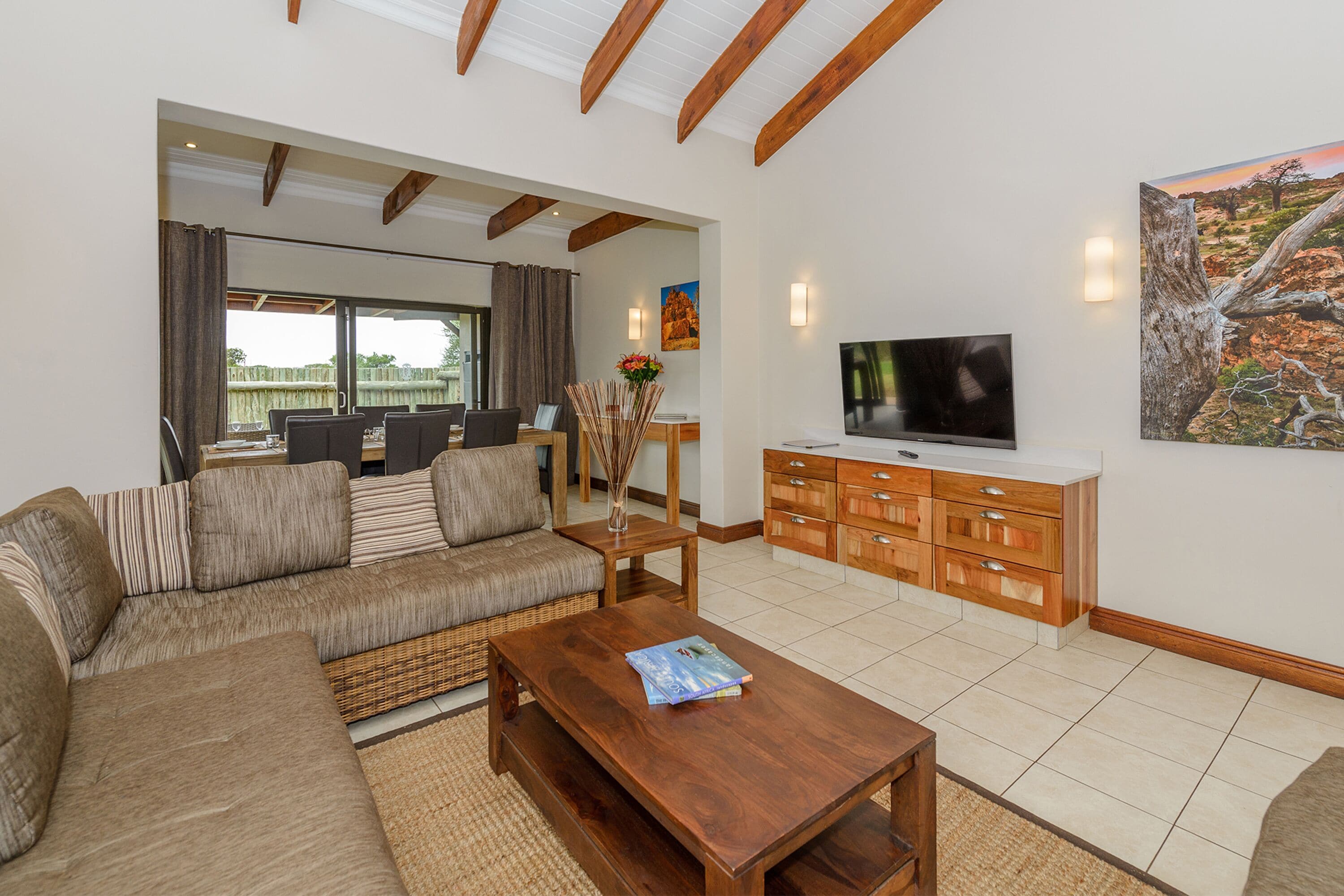 Un'ampia zona giorno con un divano grande, un tavolino in legno, una TV e un'area pranzo con tavolo e sedie.