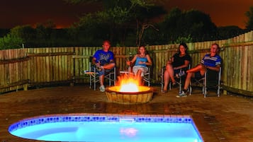 Relax by the fire pit surrounded by an outdoor space with a swimming pool and comfortable seating.