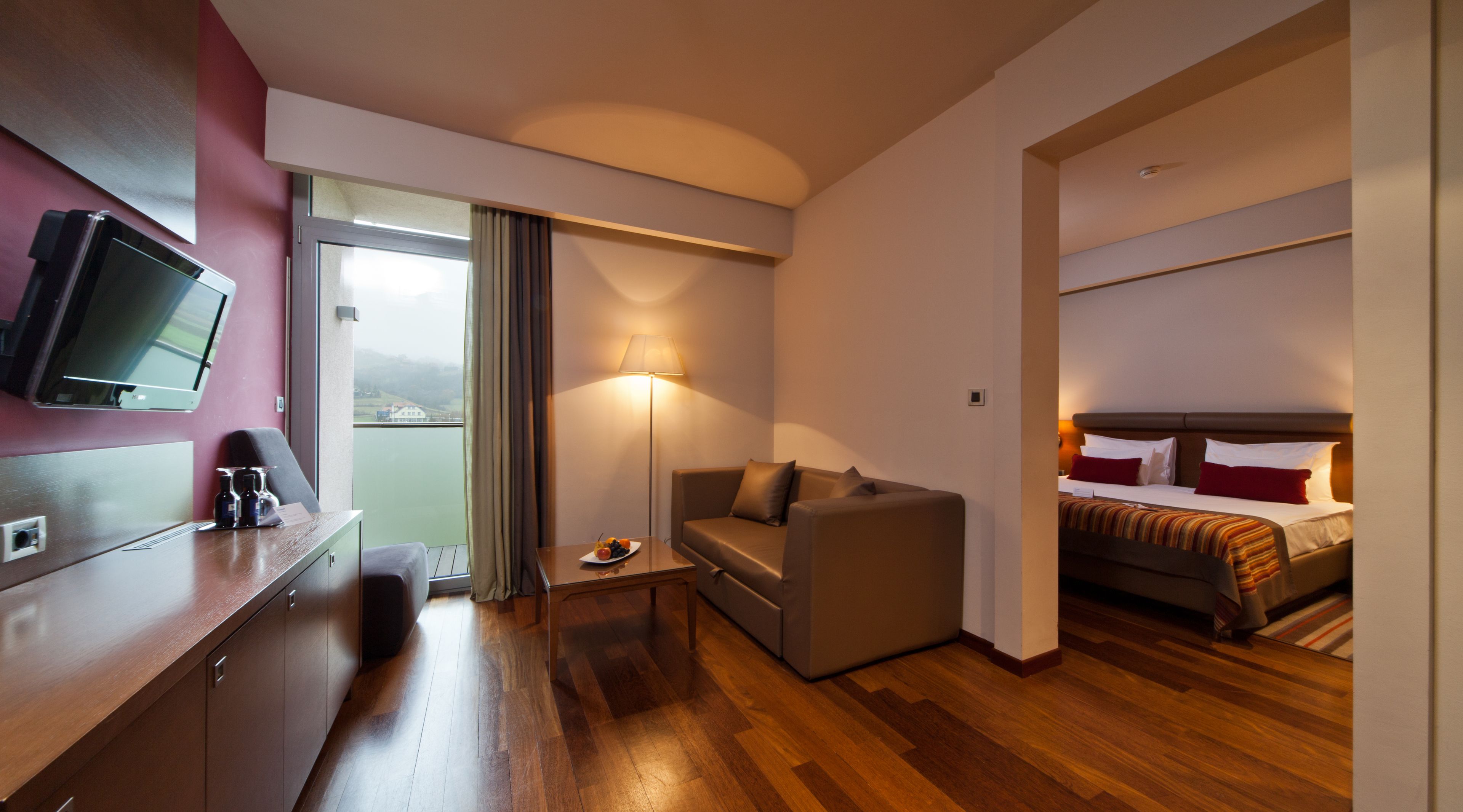 Habitación de hotel con cama, sofá, escritorio, televisor de pantalla plana y vistas al exterior.