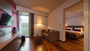 Habitación de hotel con cama, sofá, escritorio, televisor de pantalla plana y vistas al exterior.