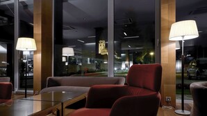 A modern interior with a glass table, red upholstered chairs, and floor lamps. - Hotel Kaj (Marija Bistrica)
