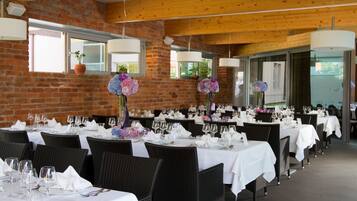 A restaurant with brick walls, wooden beams, and tables set with white tablecloths and silverware.