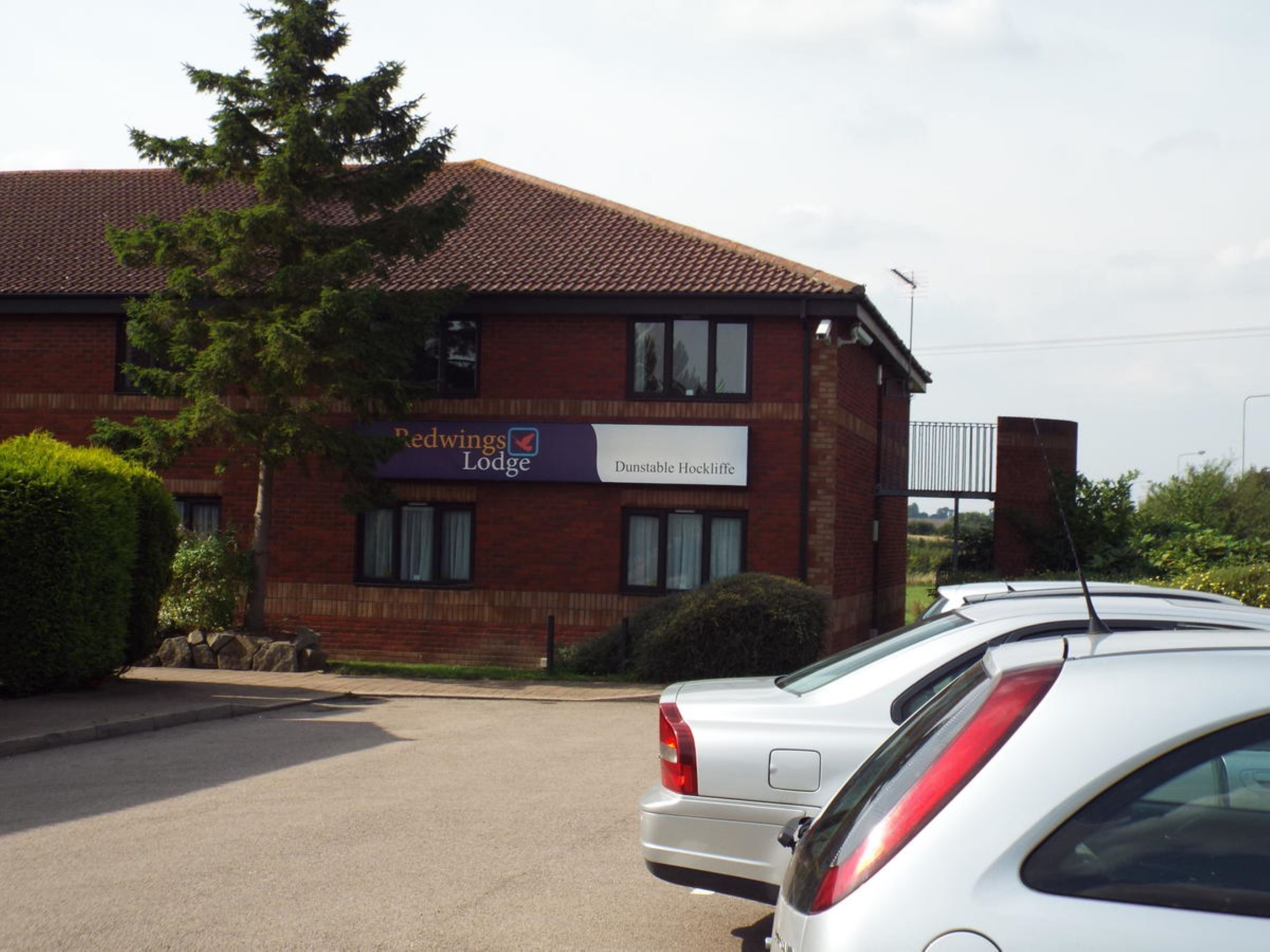 Edificio de Redwings Lodge con fachada de ladrillo y un cartel que indica que es un 'Dunstable Hocklifte'.