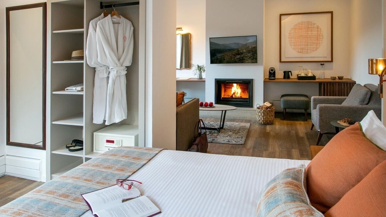 Une chambre d’hôtel comprenant un lit, un coin salon avec une cheminée, une télévision et une armoire.