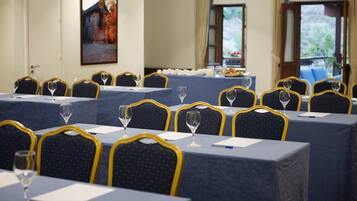 Un salón de conferencias con mesas dispuestas para reuniones, cada una con una silla y un vaso de agua.