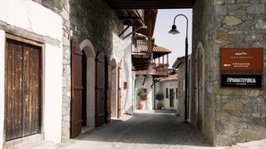 Una estrecha calle adoquinada con edificios de piedra, puertas de madera y un cartel que indica una recepción.