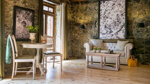 Una habitación acogedora con pared de piedra, un sofá blanco, una mesa de madera y una silla.