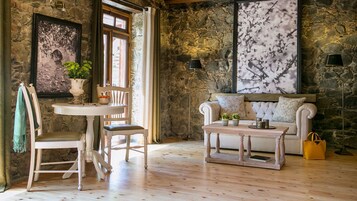 Una habitación acogedora con pared de piedra, un sofá blanco, una mesa de madera y una silla.