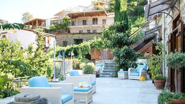 Un patio con mobiliario exterior, una escalera y vegetación circundante.