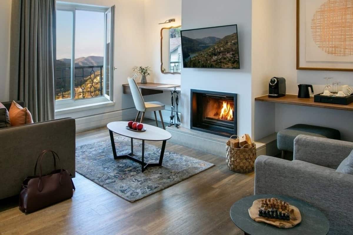 A modern living room with a fireplace, a dining area, and a view of the mountains.