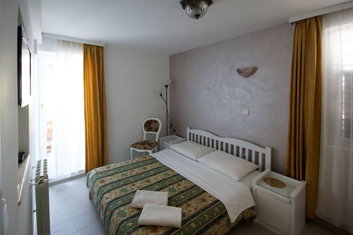 Ein ordentlich eingerichtetes Schlafzimmer mit einem Bett, einem Nachttisch, einem Sessel und einem an der Wand befestigten Regal.