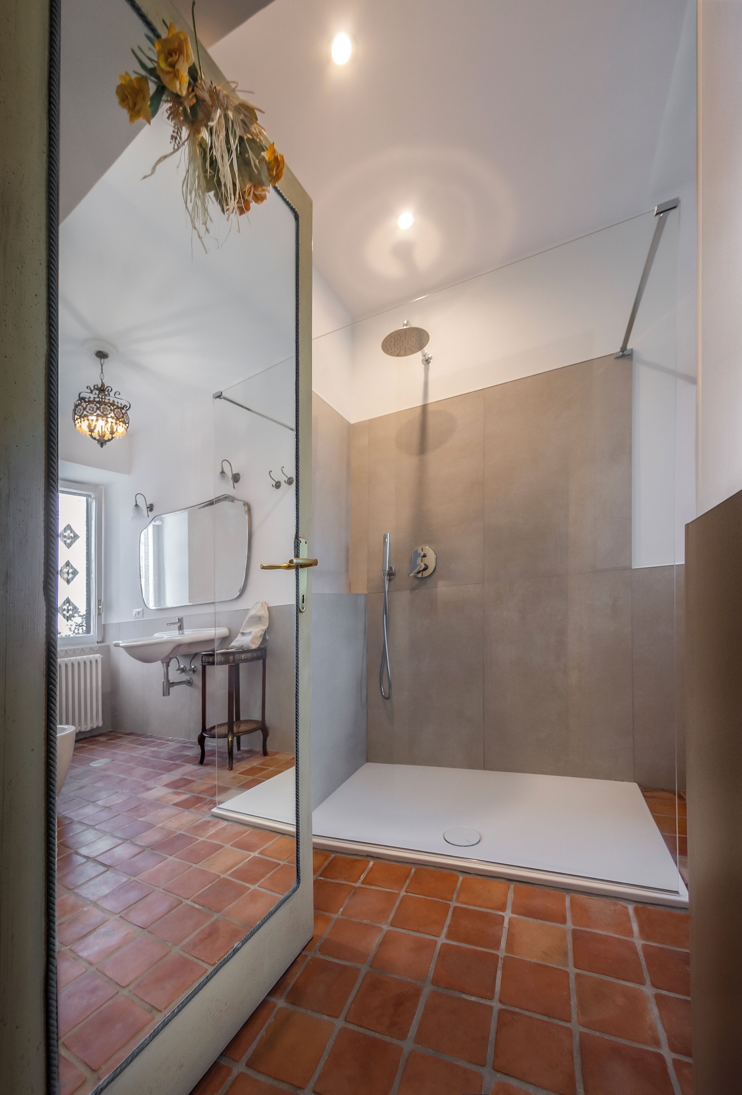 Un baño moderno con ducha a ras de suelo, un espejo grande y suelo de baldosas.