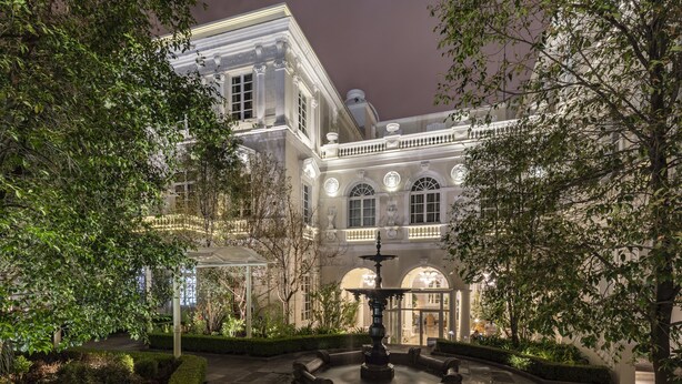 A historic building with a fountain in the courtyard, surrounded by well-maintained hedges and trees. - Casa Gangotena (Quito)
