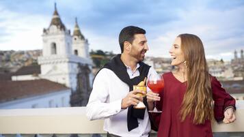 A couple on a balcony with a cityscape and a church in the background.