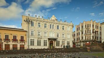A historic building with a central entrance and a large courtyard filled with pigeons.