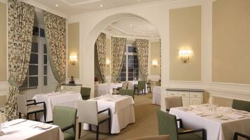 A dining area with multiple tables and chairs, elegant decor, and warm lighting.