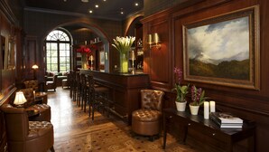 A bar area with leather seating, a bar counter, and a painting on the wall. - Casa Gangotena (Quito)