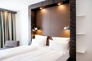 Une chambre d’hôtel moderne avec un grand lit, deux lampes de chevet et une tête de lit à motifs évoquant le bois.