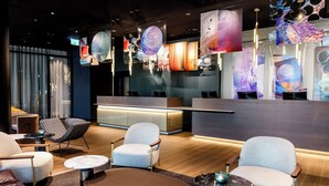 Een moderne receptie met een balie, zitplaatsen en decoratieve elementen.
