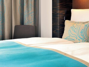 Een hotelkamer met een bed, een stoel en gordijnen.