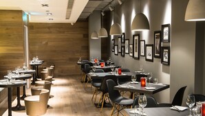 Un restaurante con varias mesas y sillas, suelo de madera y cuadros en las paredes.
