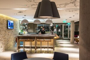 En modern bardisk med en bartender, en tegelvägg och en stor hänglampa.