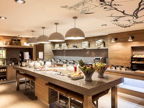 Una cocina moderna con una isla central, iluminación colgante y un salpicadero de ladrillo.