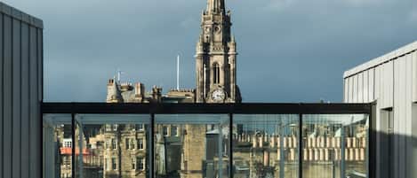 A modern building with large glass windows overlooking a historic church with a clock tower.