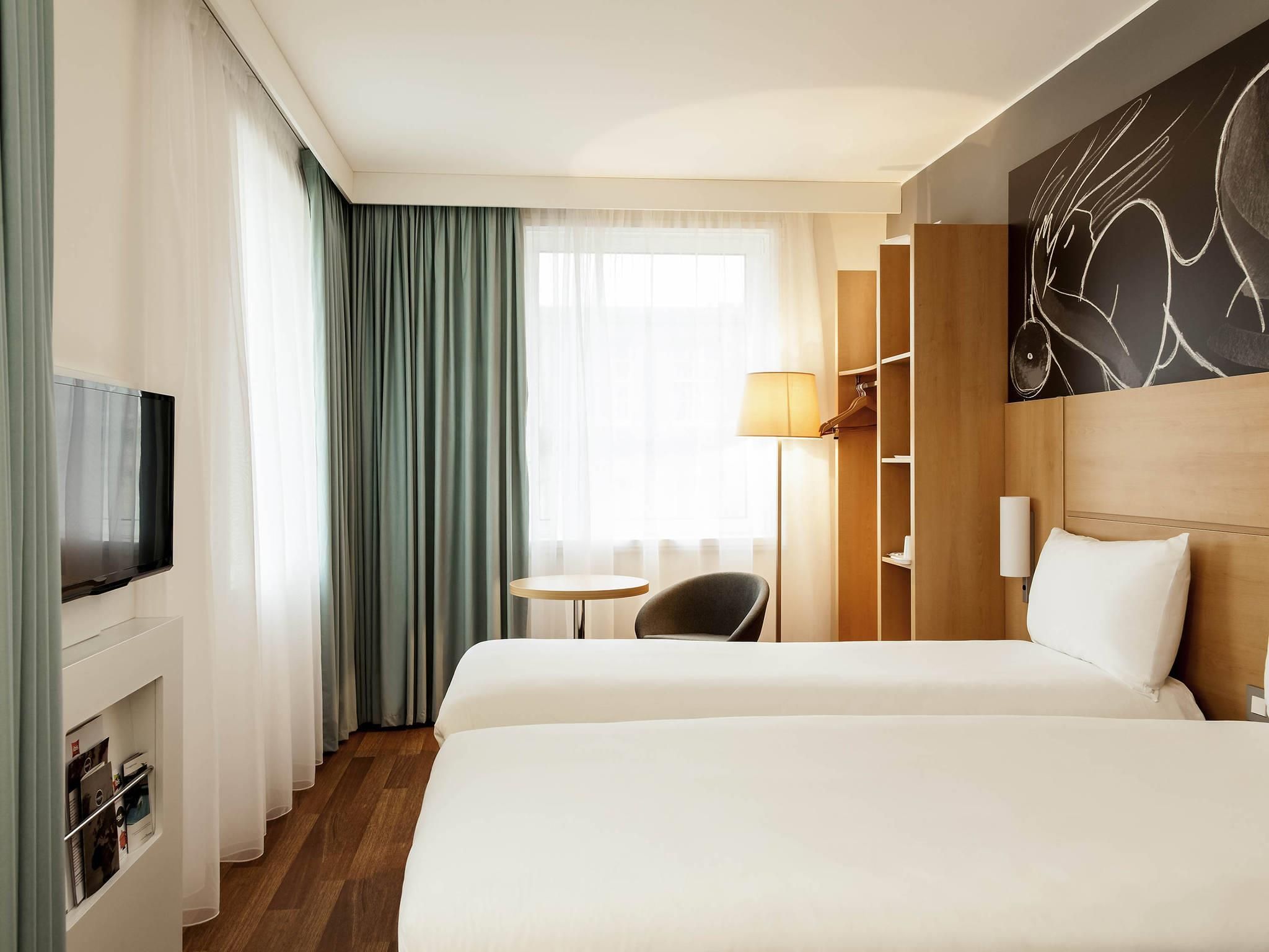 Een hotelkamer met twee bedden, een televisie, een bureau met een lamp en een kledingkast.