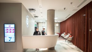 A modern reception area with a curved reception desk, a digital display, and a seating area with red curtains.