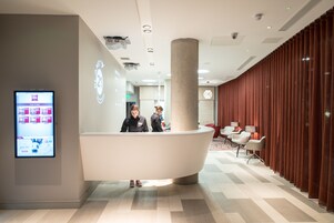 Ett modernt receptionsområde med en böjd receptionsdisk, en digital skärm och en sittgrupp med röda draperier.