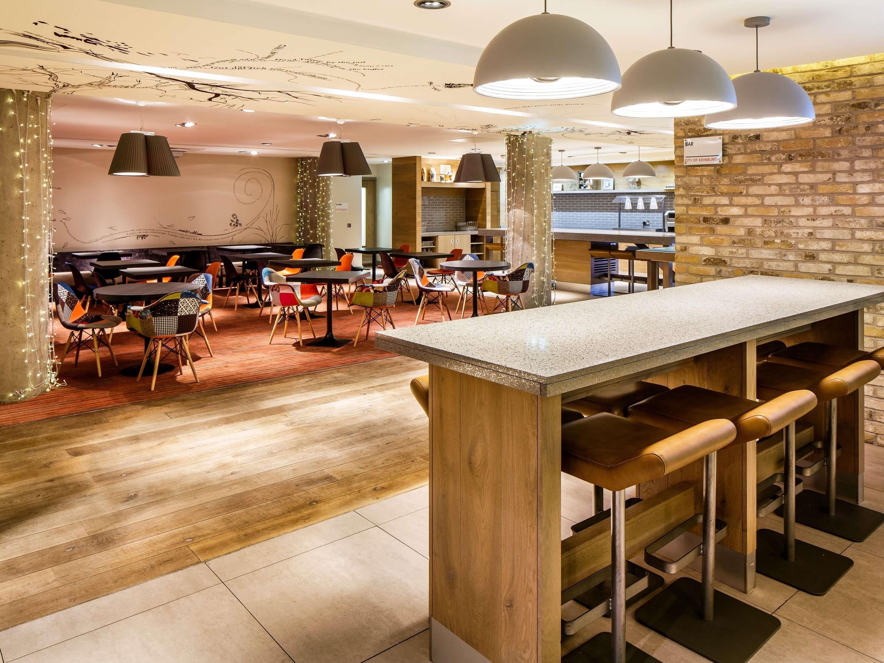 L’intérieur d’un restaurant, avec un espace bar, un plancher en bois et un éclairage moderne à suspension.