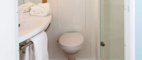 Un baño con lavamanos, inodoro y ducha blancos.