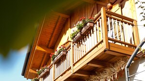 Een houten balkon met bloembakken en een decoratieve guirlande.