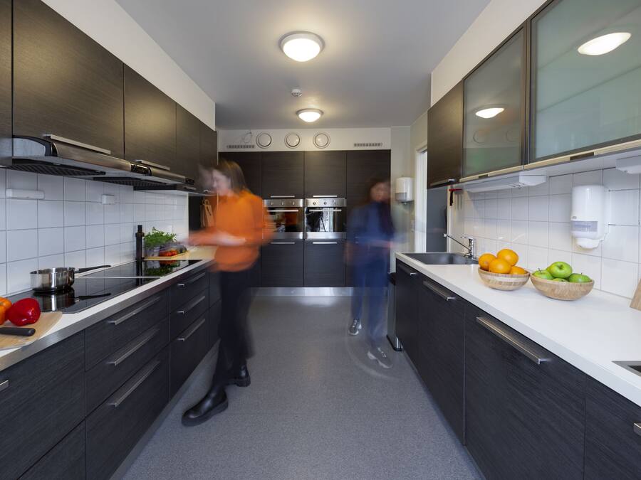 Una cocina moderna con gabinetes oscuros, encimeras blancas y electrodomésticos de acero inoxidable.