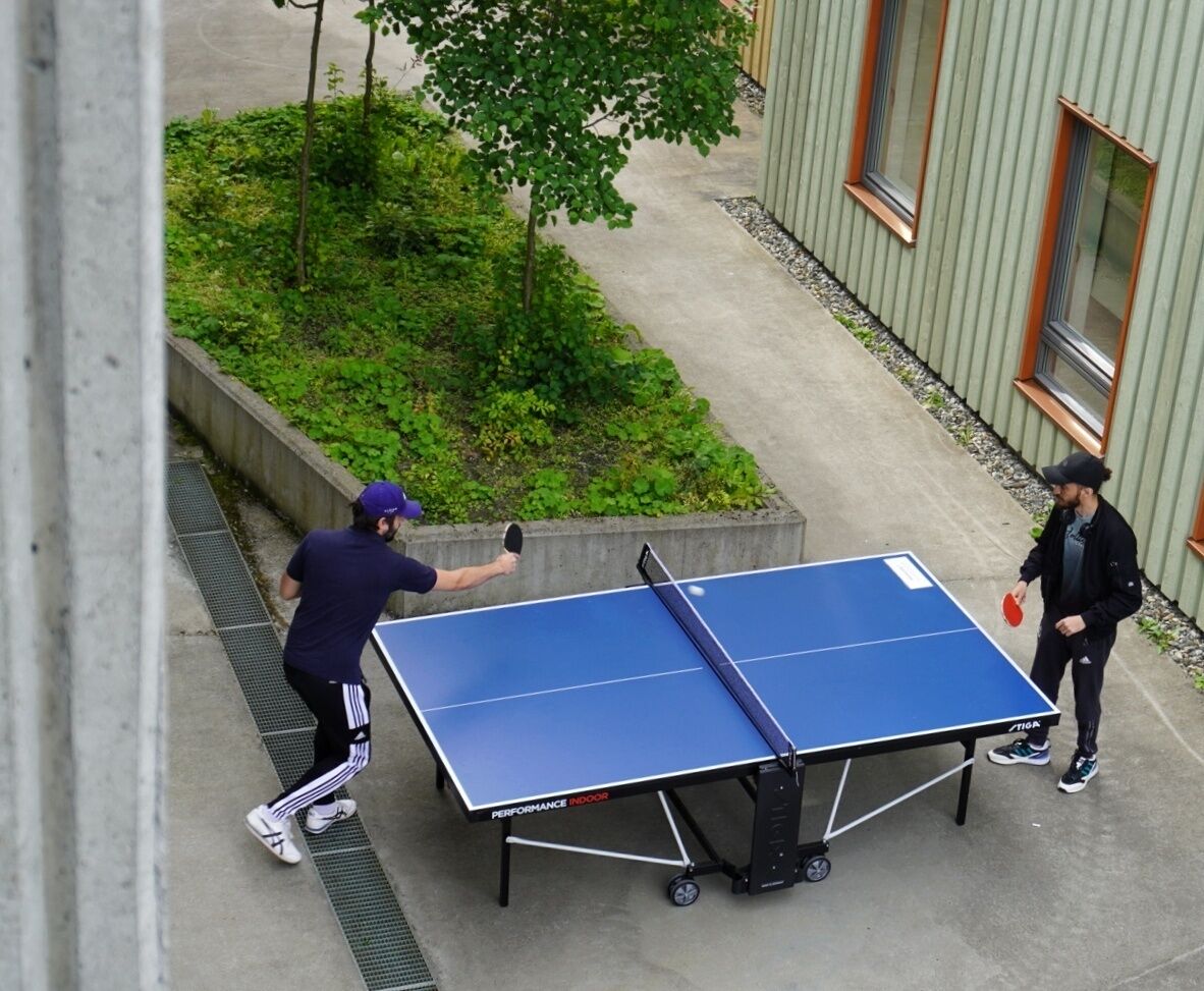 Deux personnes jouent au ping-pong à l’extérieur, sur une table portable.