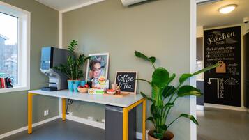 A kitchen area with a chalkboard sign reading "Coffee & Tea," a coffee machine, and a trash bin.